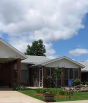 Exterior view of Medicalodges Columbus facility with entrance, porch, and landscaped garden.