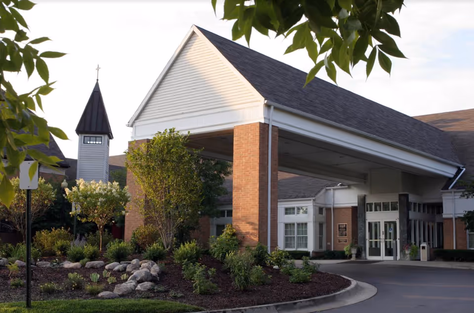 Entrance to a brick senior living facility with landscaped garden and covered driveway.