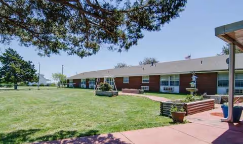 Exterior view of Moran Manor: a single-story brick building with a green lawn and planters.