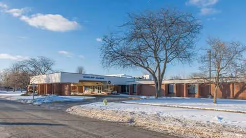 Snowy parking area and leafless trees frame Avista Nursing and Rehab's brick building exterior.