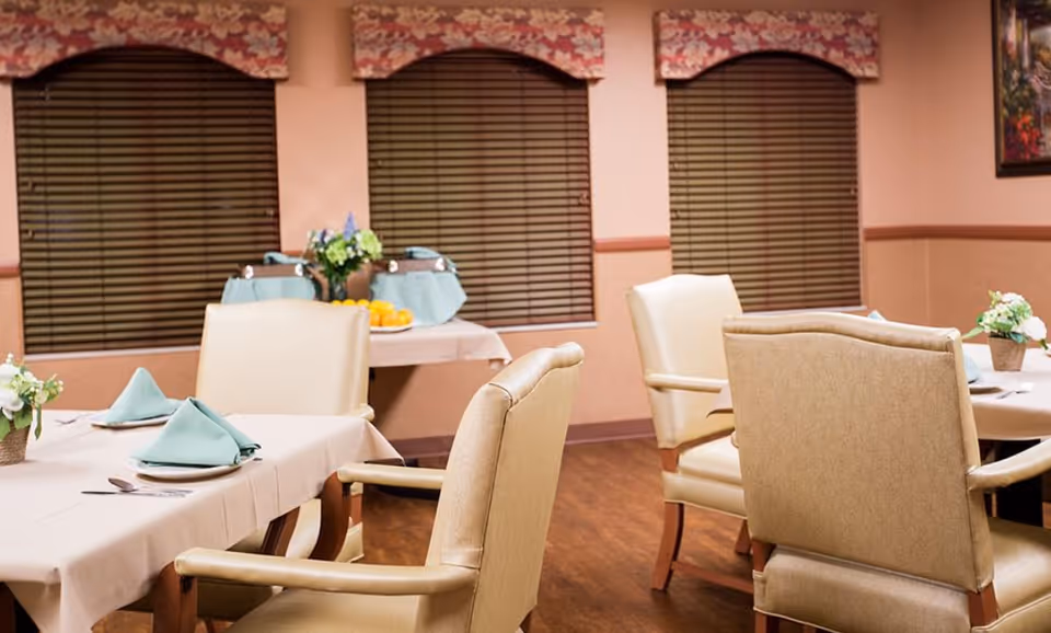 Elegant dining room with set tables, napkins, and beige upholstered chairs.