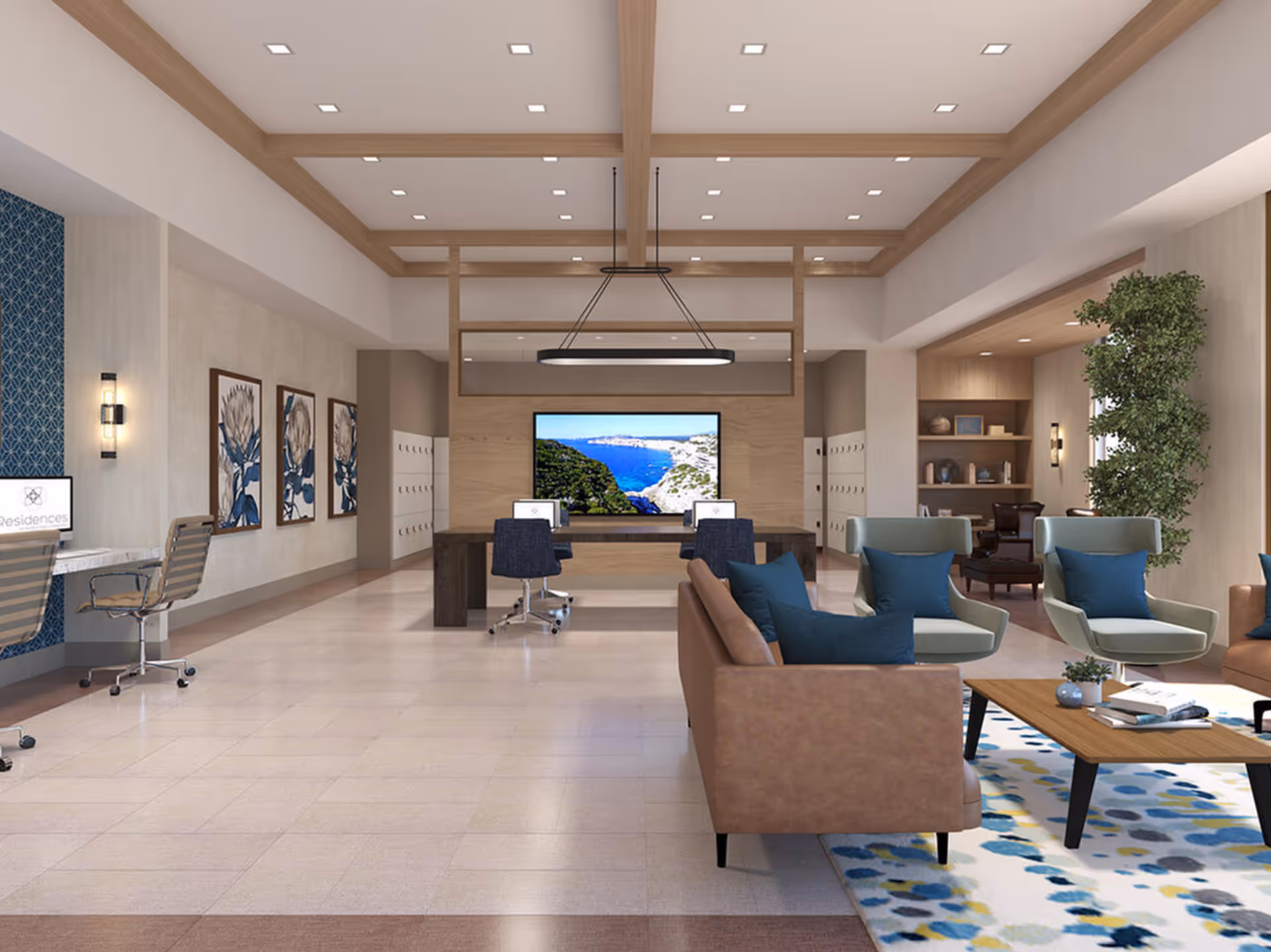 A spacious and modern common area with a seating arrangement including brown sofas and light green armchairs with blue cushions around a wooden coffee table on a patterned rug. In the background, there are two desks with office chairs and computer monitors, a large screen displaying a coastal landscape, framed floral artwork on the wall, and a tall green plant near a bookshelf.
