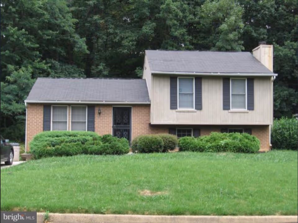 Two-story suburban building with brick and beige siding, surrounded by trimmed bushes and a lawn.
