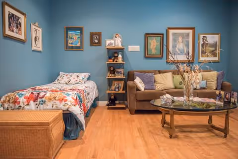 Teal-walled living area featuring a bed, sofa, coffee table, and wall art.
