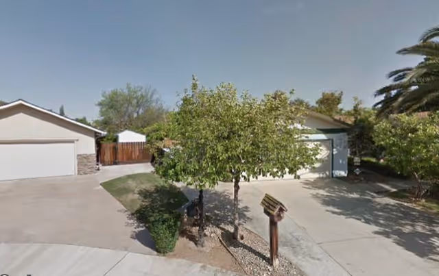 Front exterior of a senior care home with driveway, trees, and garages.