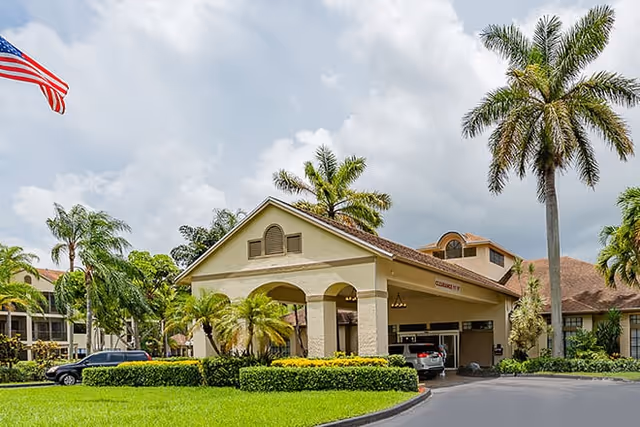 Front entrance of Waterside Landing senior living facility with a porte-cochere, palm trees, and parked cars.
