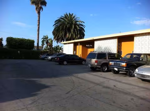 Parking lot in front of Santa Fe Heights Healthcare Center, with palm trees and parked cars.