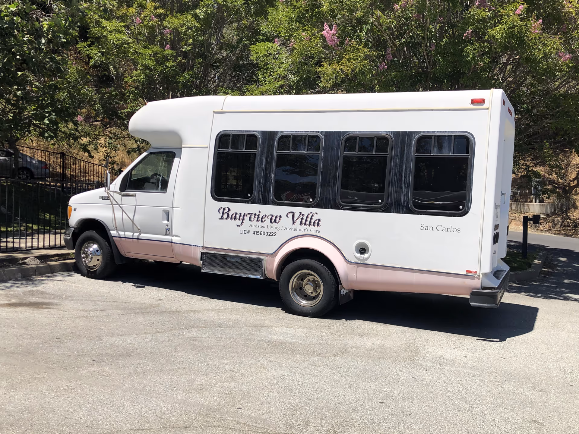 White Bayview Villa shuttle bus parked on a driveway under trees