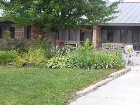 Exterior view of Vernon Manor with greenery, benches, and patio seating in front of the building.