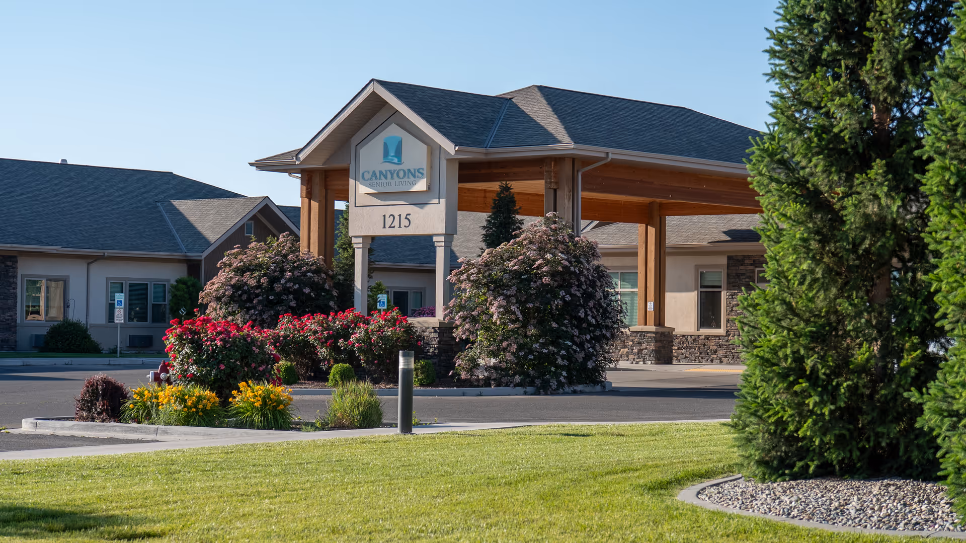 Front entrance of Canyons Senior Living with a covered porte-cochère, address 1215, and landscaped flower beds.