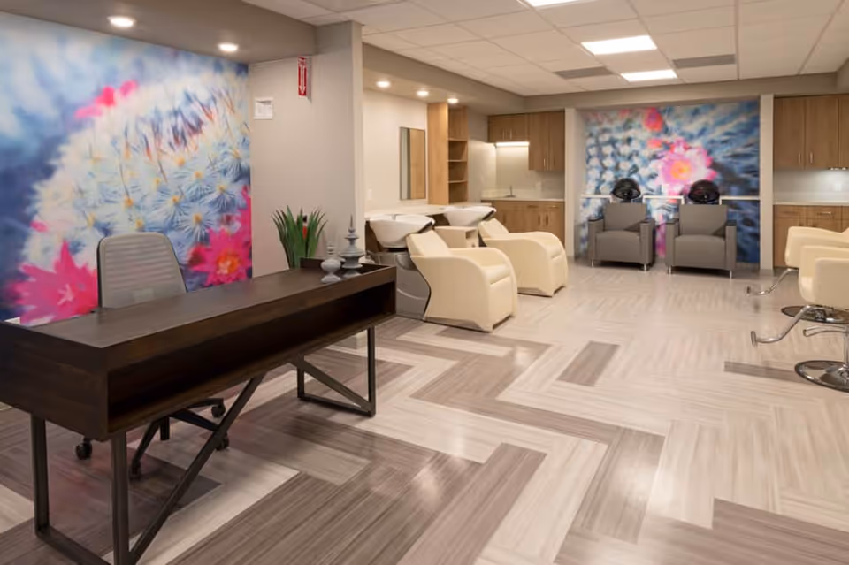 Bright, modern salon area with styling chairs, shampoo stations, a desk, and colorful floral wall murals.