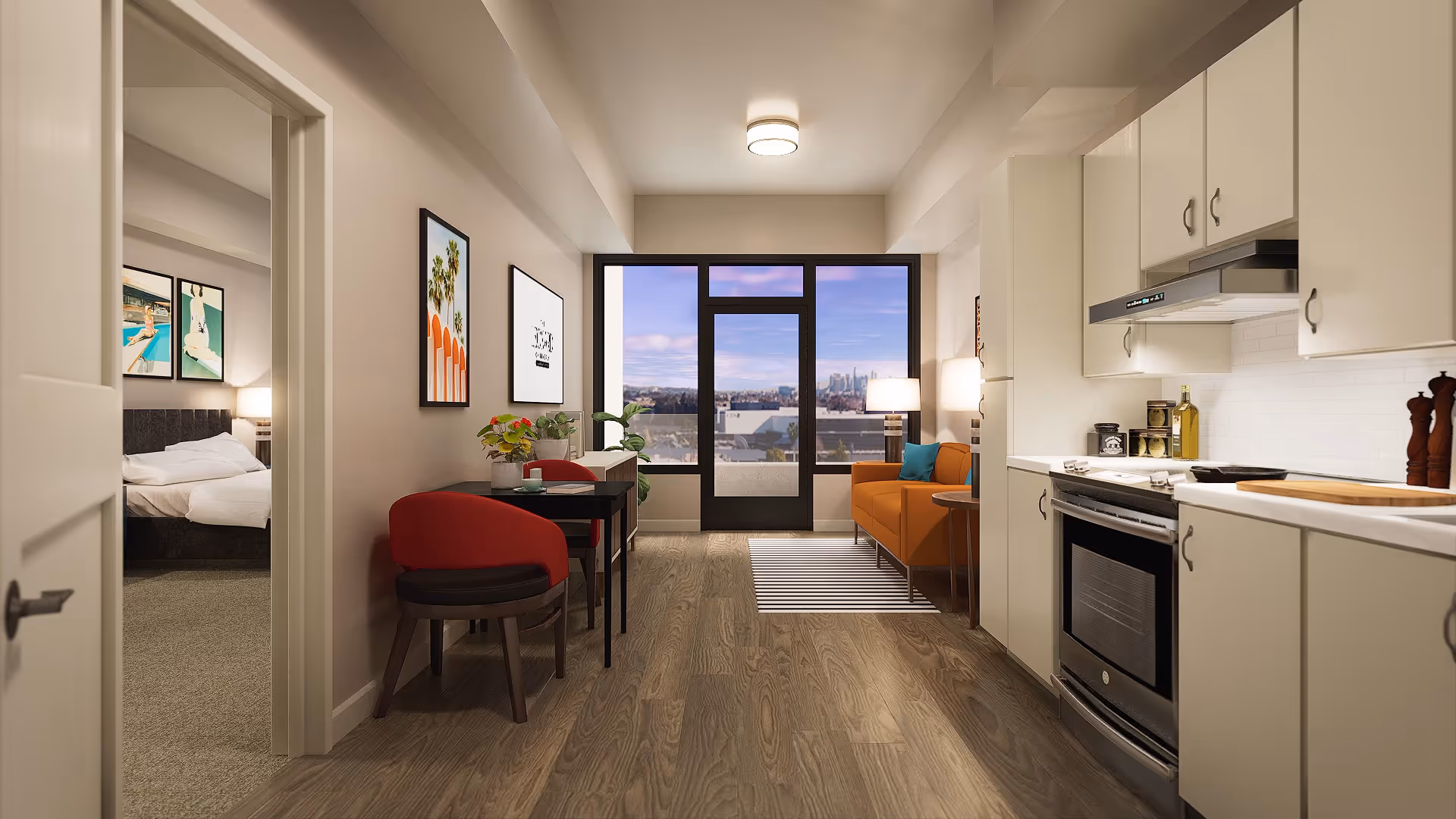 Open-plan apartment interior with a kitchenette on the right, a small dining table and living area with an orange sofa facing a balcony, and a bedroom visible through a doorway.