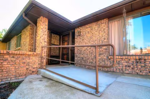 Brick exterior entrance with a metal ramp and railing.