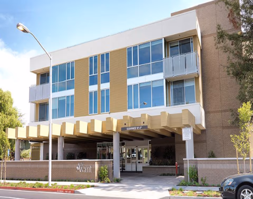 Exterior of The Avant senior living facility with balconies and large glass windows.