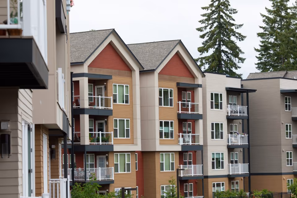 Exterior view of a multi-story apartment building with balconies, windows, and nearby trees.