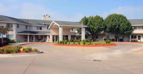 Exterior view of a two-story senior living facility with a roundabout and manicured landscaping.