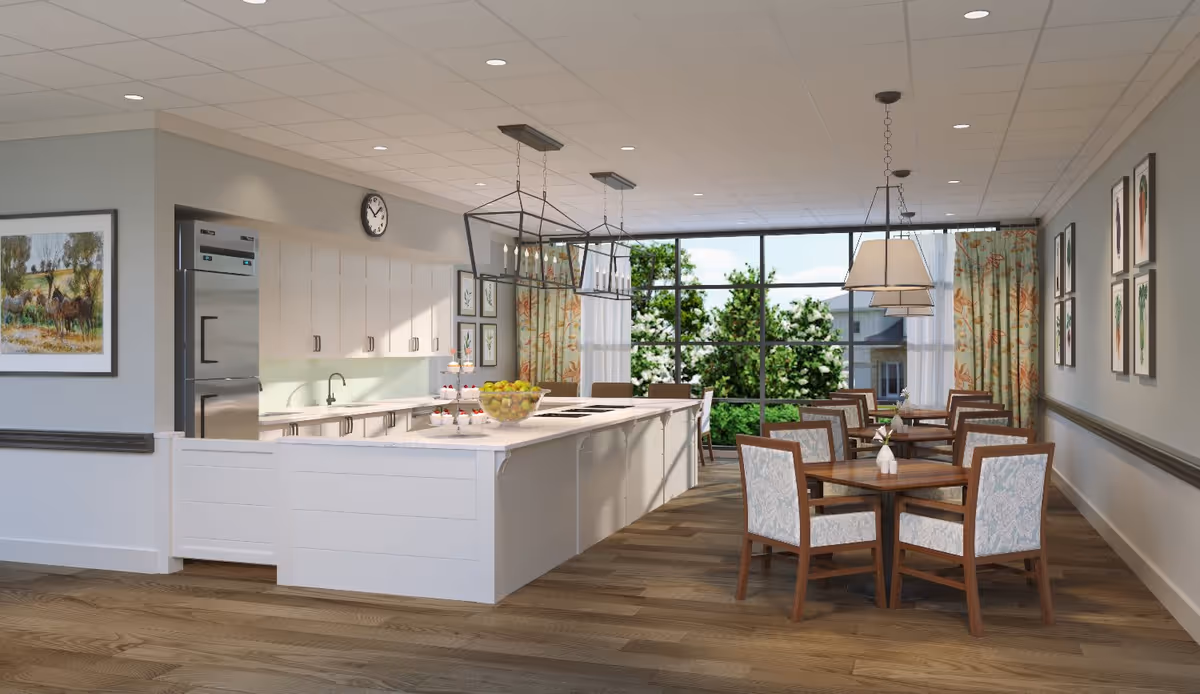 Bright communal dining area with tables and chairs and an open kitchen island, large windows, and pendant lighting.