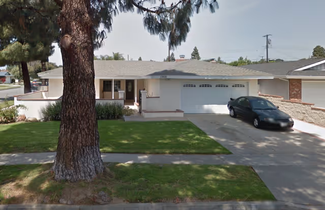 Single-story house with attached garage, front lawn, and parked dark sedan.