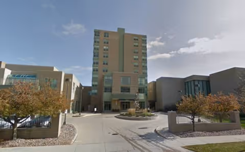 Exterior view of a multi-story senior living facility with a central entrance.