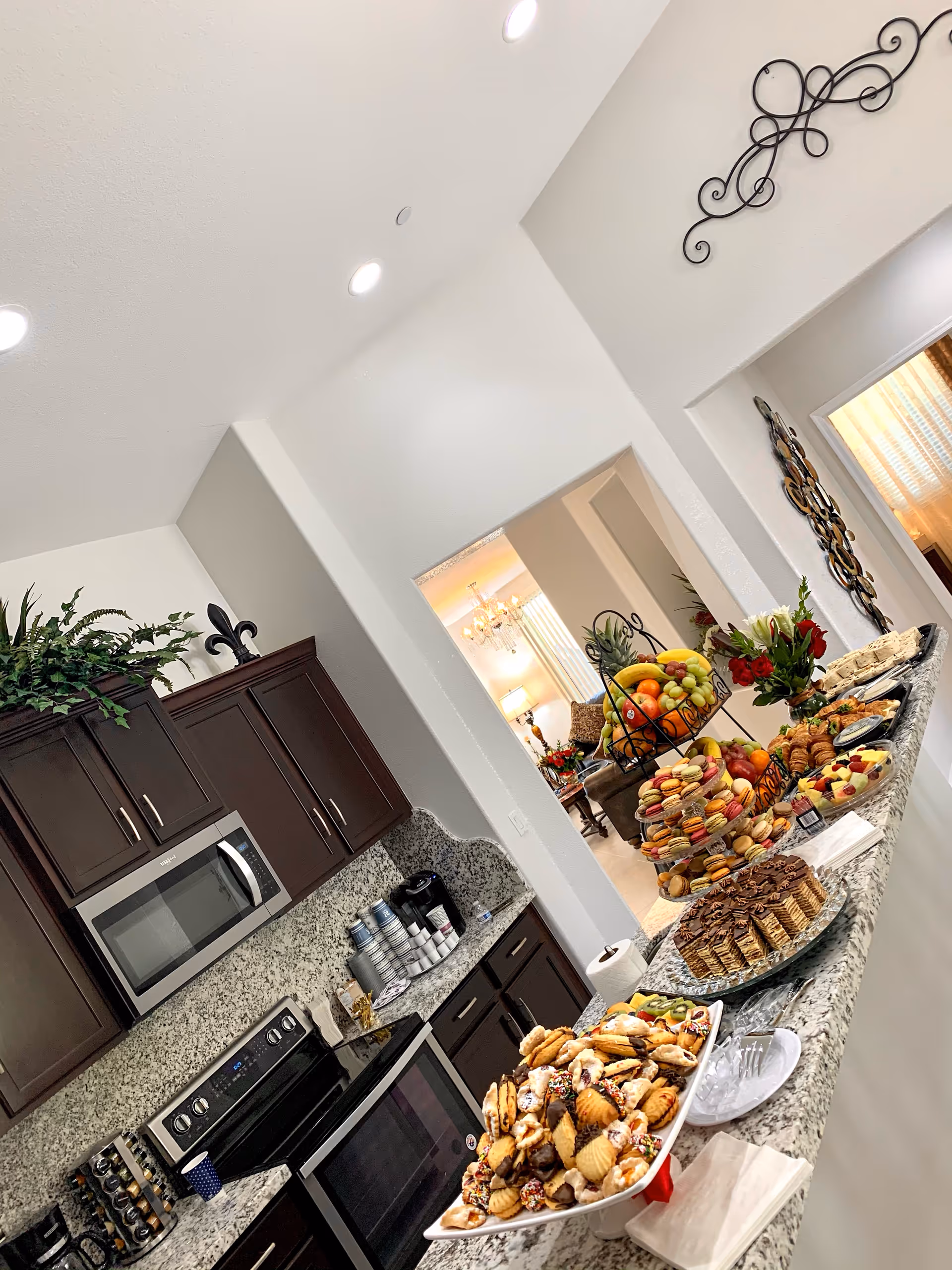 Open kitchen with granite countertops, dark cabinets and a long buffet of pastries, desserts and fruit.