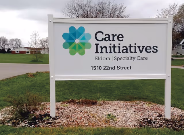 Outdoor sign reading "Care Initiatives Eldora | Specialty Care, 1510 22nd Street" on a white frame set in a grassy lawn.