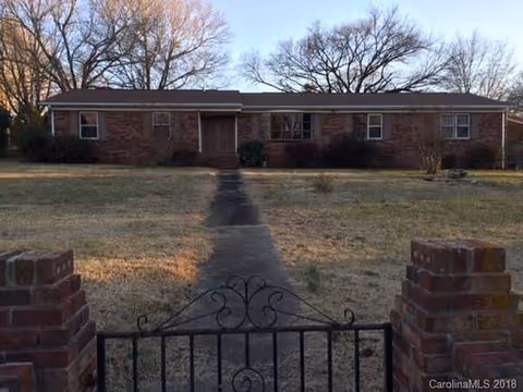 Exterior of Autumn Years Retirement Center: single-story brick building, path to entrance, wrought-iron gate.