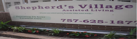 Front exterior sign for Shepherd's Village Assisted Living with greenery along a brick walkway.