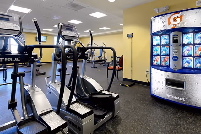 Exercise room with elliptical machines and a Gatorade vending machine in a senior living facility.