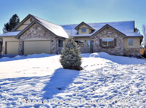Front exterior view of a stone-facade assisted living home covered in snow
