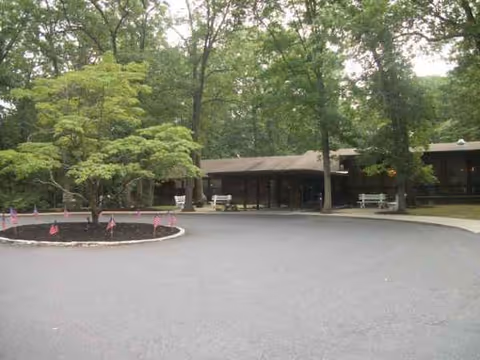 Exterior view of Big Oak Rehab facility with circular driveway, trees, and benches