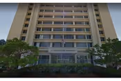 Westminster Gardens building: tall residential front with glass entry, flag, and greenery.