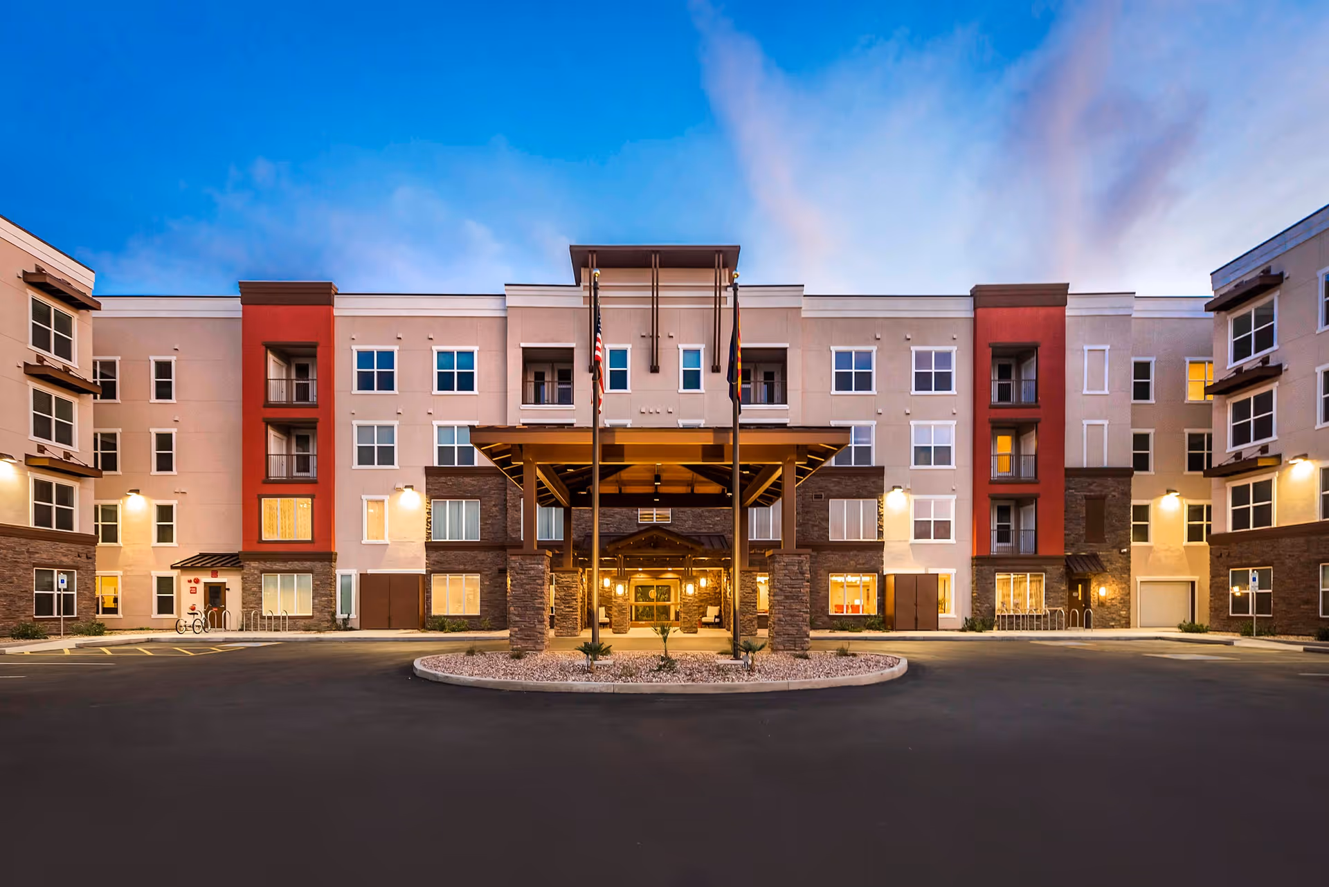 Modern four-story senior living building with a covered entrance and circular driveway.