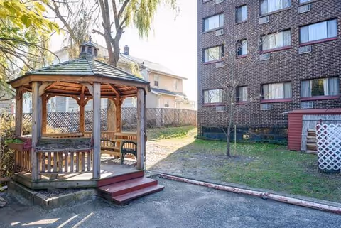 Wooden gazebo in New Haven Manor courtyard beside a brick building.