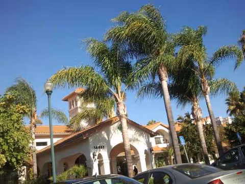 Exterior view of Oakmont of Chino Hills with palm trees and parked cars.