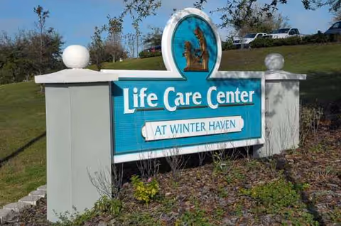Outdoor Life Care Center sign on a landscaped lawn with parked cars in background