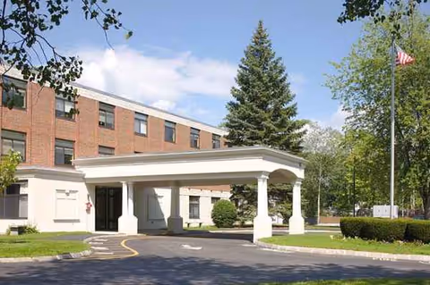 Harris Hill Center building with a white portico entrance and green lawn.