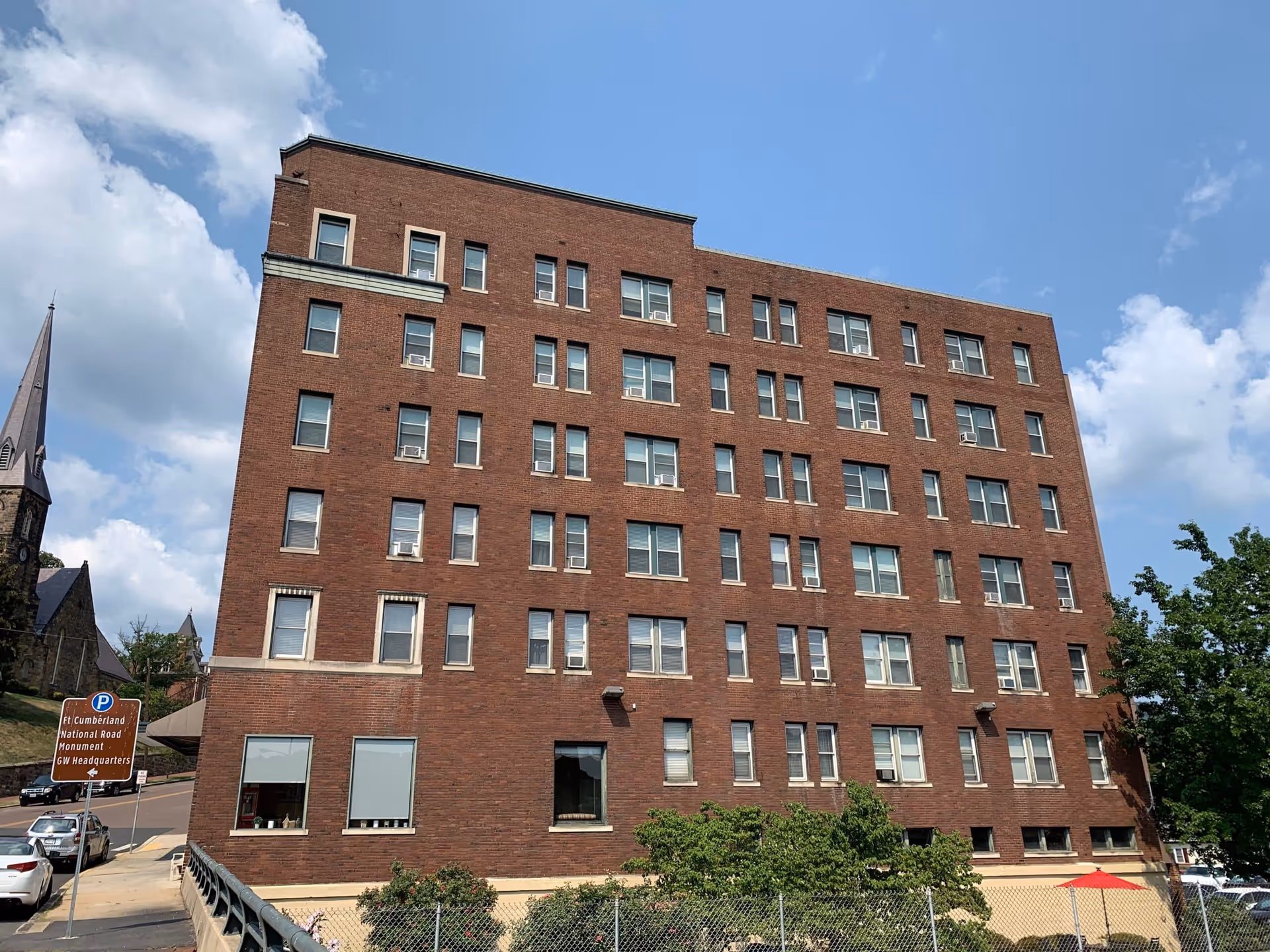 Front exterior of a brick, multi-story senior living building with many windows.