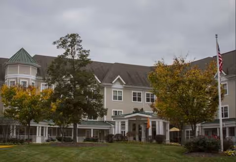 Sunrise of Columbia exterior front view with entrance, lawn, and trees.