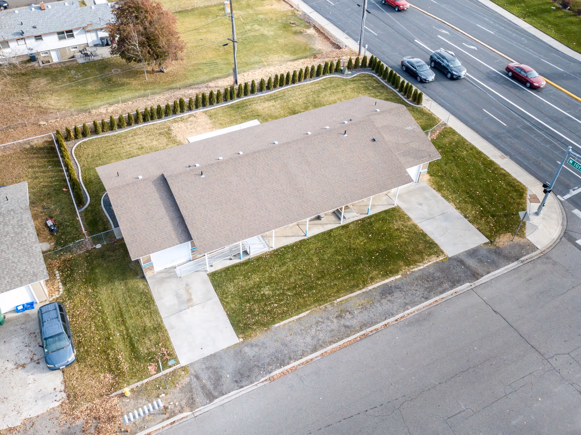 Aerial view of a single-story residential building with driveways, lawn, and nearby street intersection.