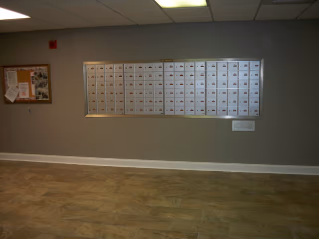 A bank of community mailboxes mounted on a lobby wall with a bulletin board to the left.