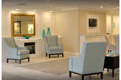 Bright lounge with upholstered armchairs, a fireplace mantel, decorative mirror and vases.