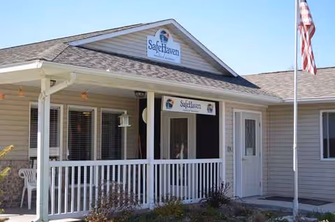 Front exterior of Safe Haven Healthcare building with porch, railing, and American flag.