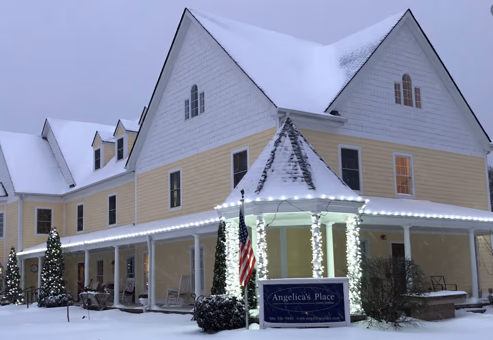 Snowy exterior of Angelica's Place senior living facility with a wraparound porch.