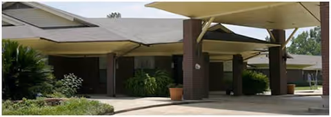 Front entrance of a senior living facility with brick columns and shaded canopies.