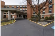 Brick senior living facility entrance with a covered drop-off and landscaped approach.