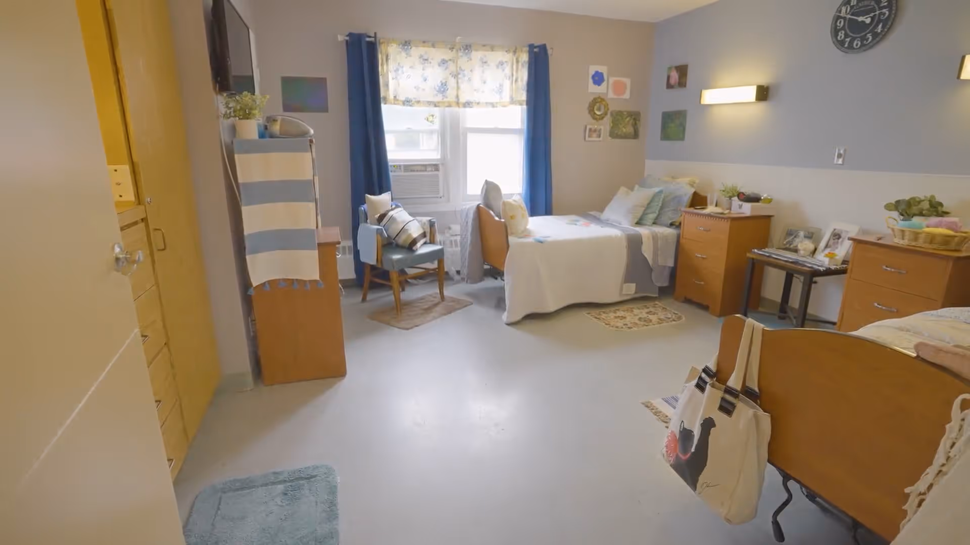 Bright shared senior bedroom with two beds, wooden dressers, a chair by a window, and personal decor.
