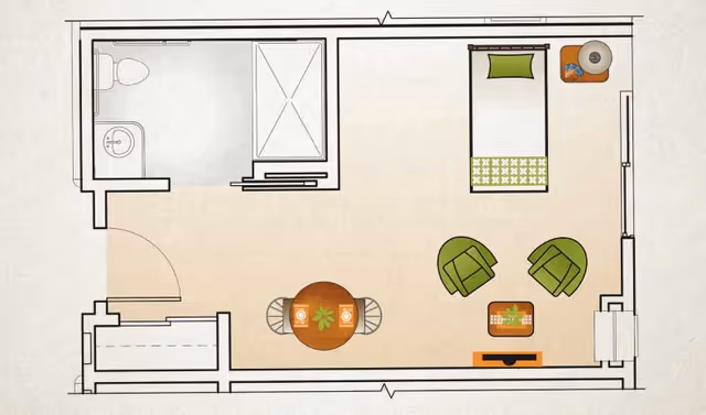 Floor plan of a small studio apartment with a bathroom in the upper left corner, a bed in the upper right corner, two green chairs and a coffee table in the lower right area, and a round dining table with two chairs in the lower left area.