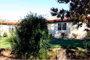 Exterior view of Riverbank Post-Acute building with lawn, shrubs, and a tree.