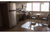 A bright kitchen area with stainless steel refrigerator, microwave, and stove. There is a small round dining table with two chairs near a large window letting in natural light.