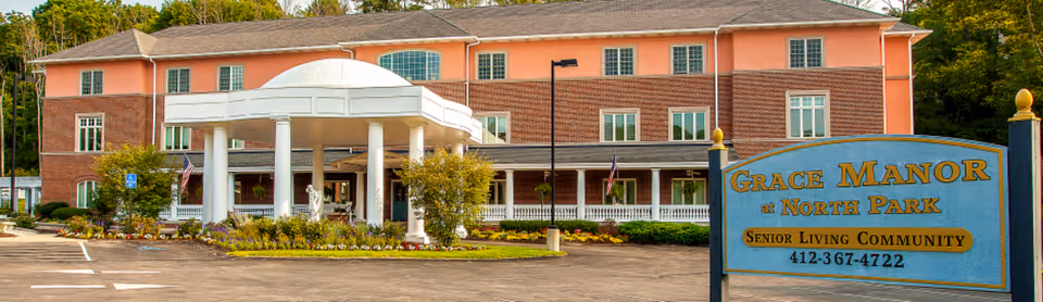 Front exterior of Grace Manor at North Park senior living community showing the building entrance with white columns and a large sign.